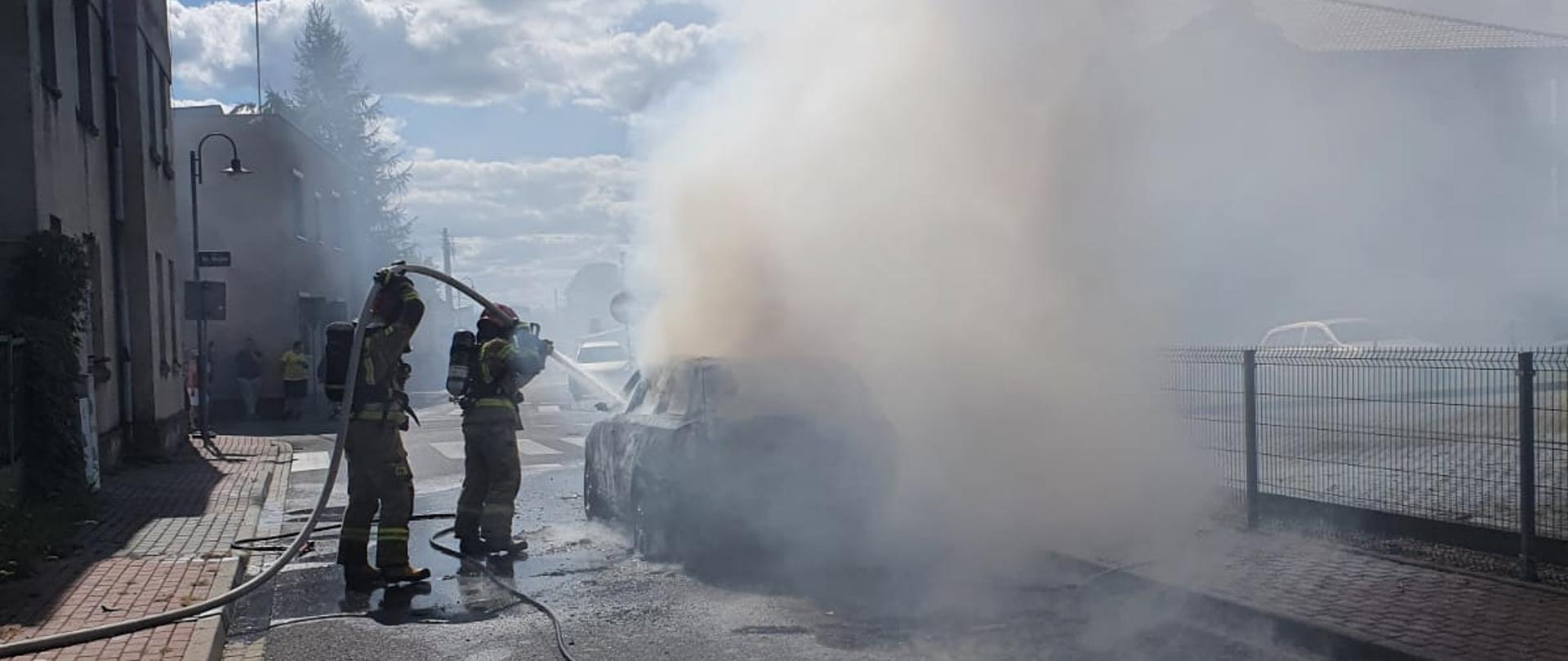 Na zdjęciu widać strażaków gaszących samochód 