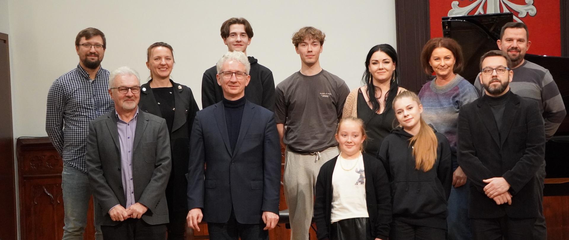Grupa uczniów i nauczycieli pozuje do wspólnego zdjęcia po warsztatach pianistycznych prowadzonych przez dr. hab. Macieja Pabicha z Akademii Muzycznej w Poznaniu.
