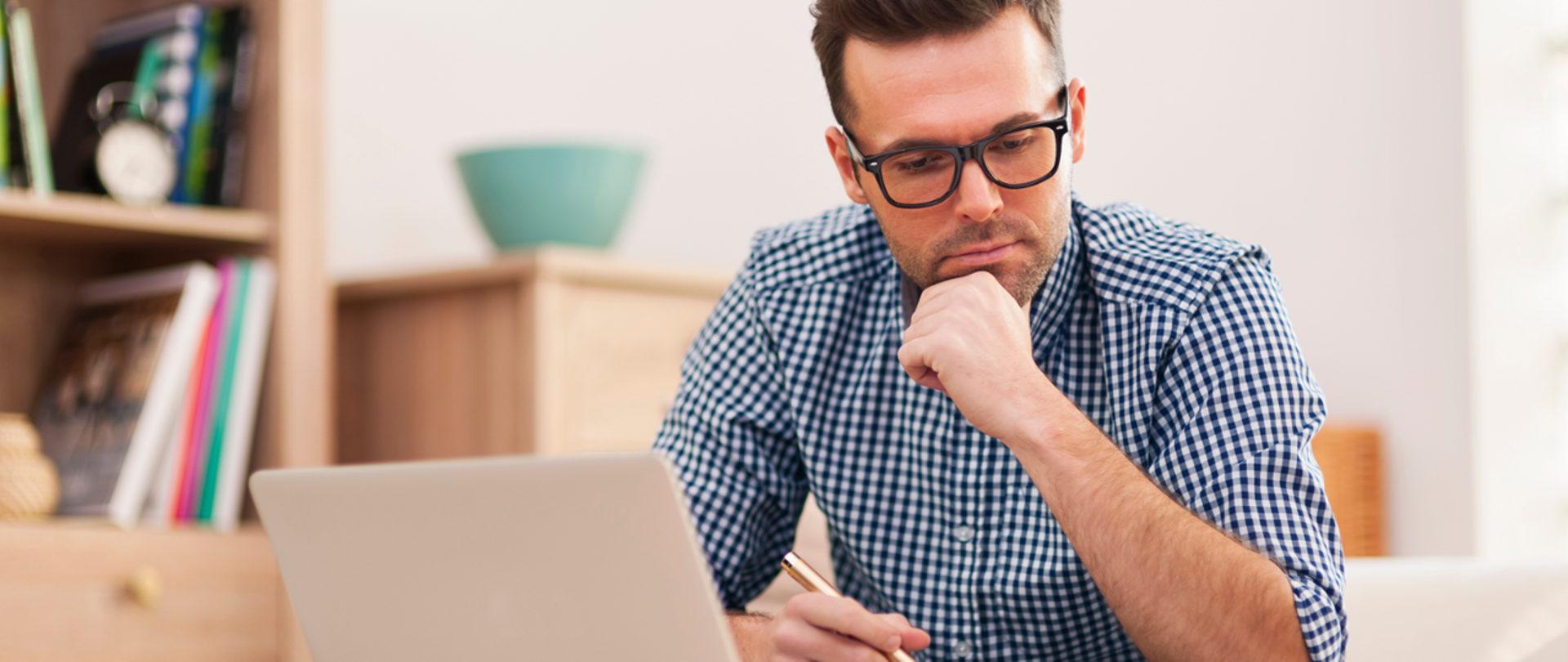 Mężczyzna w okularach patrzy na dokumenty leżące na stole