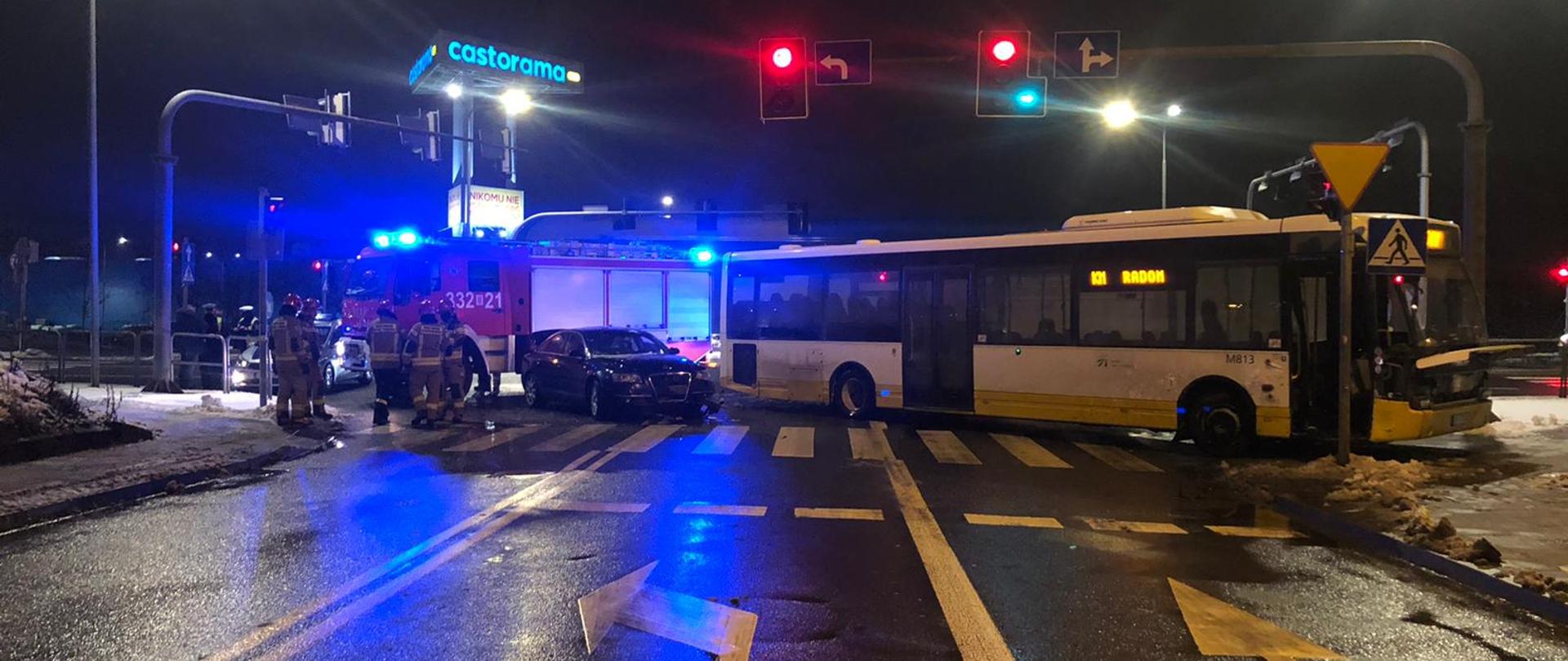 Zdjęcie przedstawia wypadek samochodów: osobowego i autobusy. Na zdjęciu widać uszkodzone pojazdy, strażaków i pojazd ratowniczy. Zdarzenie ma miejsce w porze wieczorowej.
