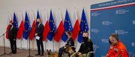 Na zdjęciu Minister Spraw Wewnętrznych i Administracji oraz funkcjonariusze służb mundurowych i ich psy podczas konferencji