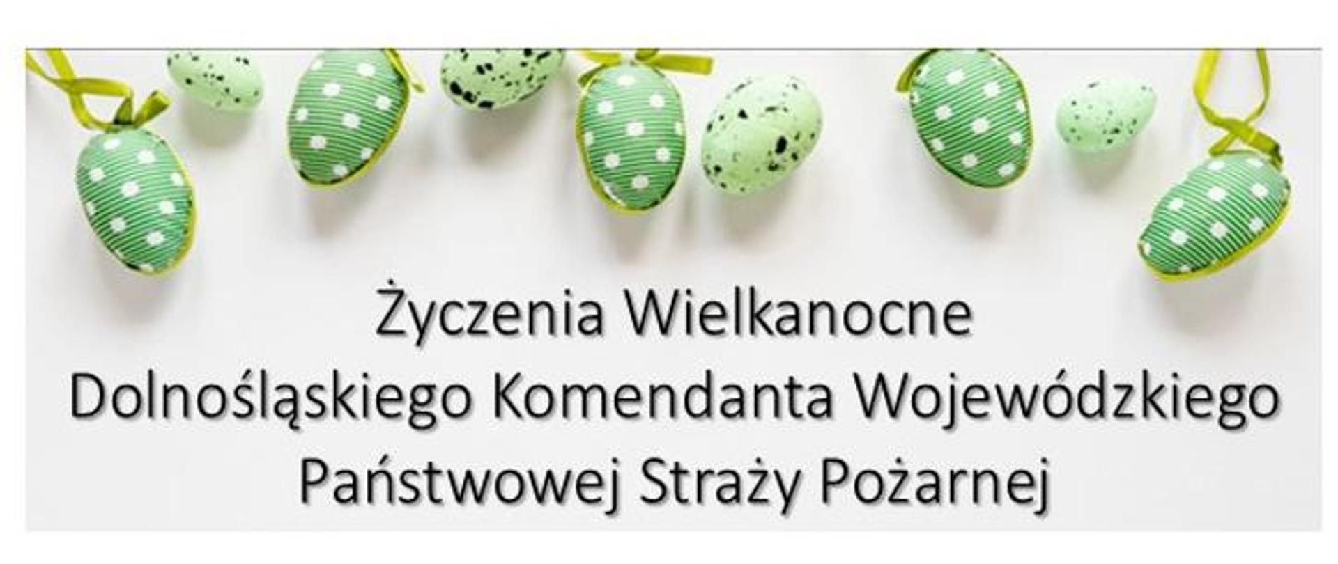 Grafika świąteczna z życzeniami wielkanocnymi. Na białym tle umieszczono dekoracyjne zielone pisanki zawieszone na wstążkach. W centralnej części znajduje się napis: „Życzenia Wielkanocne Dolnośląskiego Komendanta Wojewódzkiego Państwowej Straży Pożarnej”. Grafika utrzymana jest w jasnej, wiosennej kolorystyce nawiązującej do Świąt Wielkanocnych.