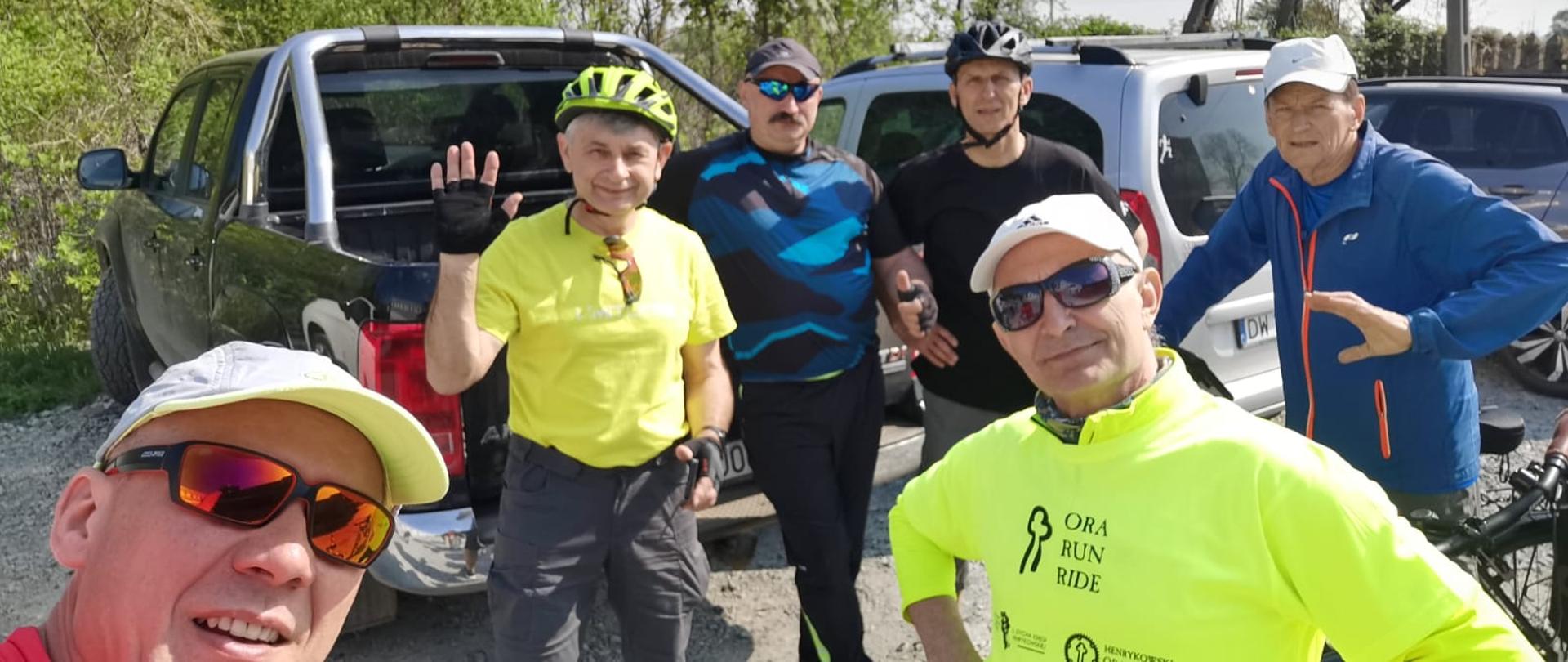 Sześciu uczestników Rajdu w strojach sportowych przygotowujących się do wyruszenia w trasę na rowerach