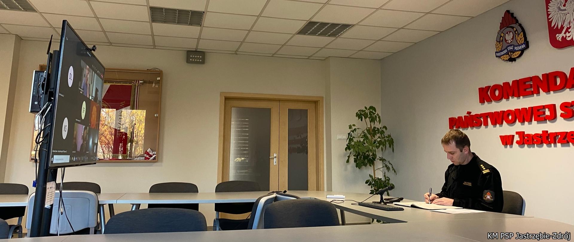 Komendant PSP w Jastrzębiu-Zdroju siedzi przy biurku podpisując dokumenty