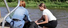 trzy dziewczyny układają na pomoście manekina wyjętego z rzeki w pozycji bocznej ustalonej