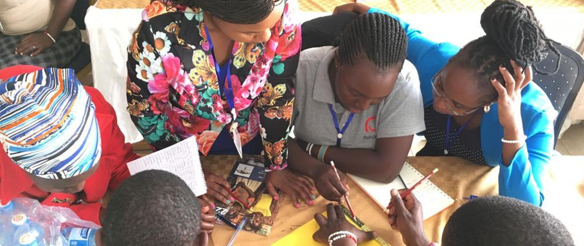 Przy stole siedzi grupa nauczycielek i nauczycieli i korzysta z pomocy dydaktycznych