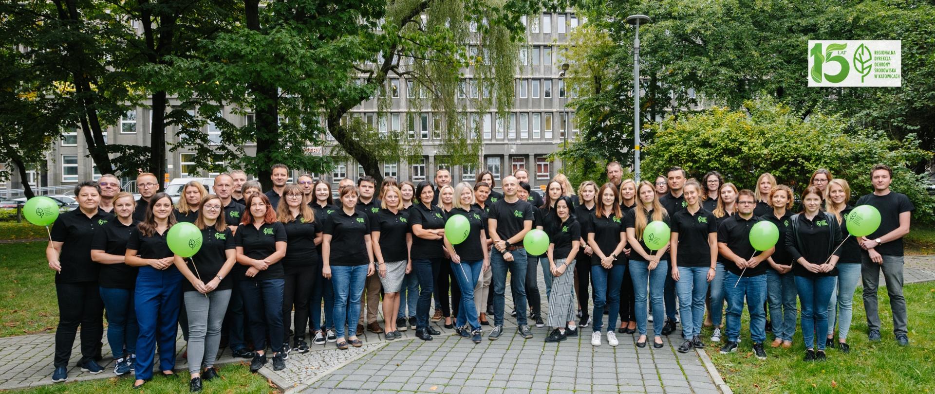 zdjęcie przedstawia grupę ludzi w czarnych koszulkach z balonami w parku