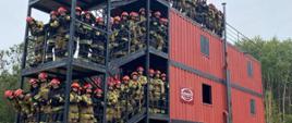 Komora rozgorzeniowa na schodach której ustawieni są strażacy biorący udział w honorowej wspinaczce