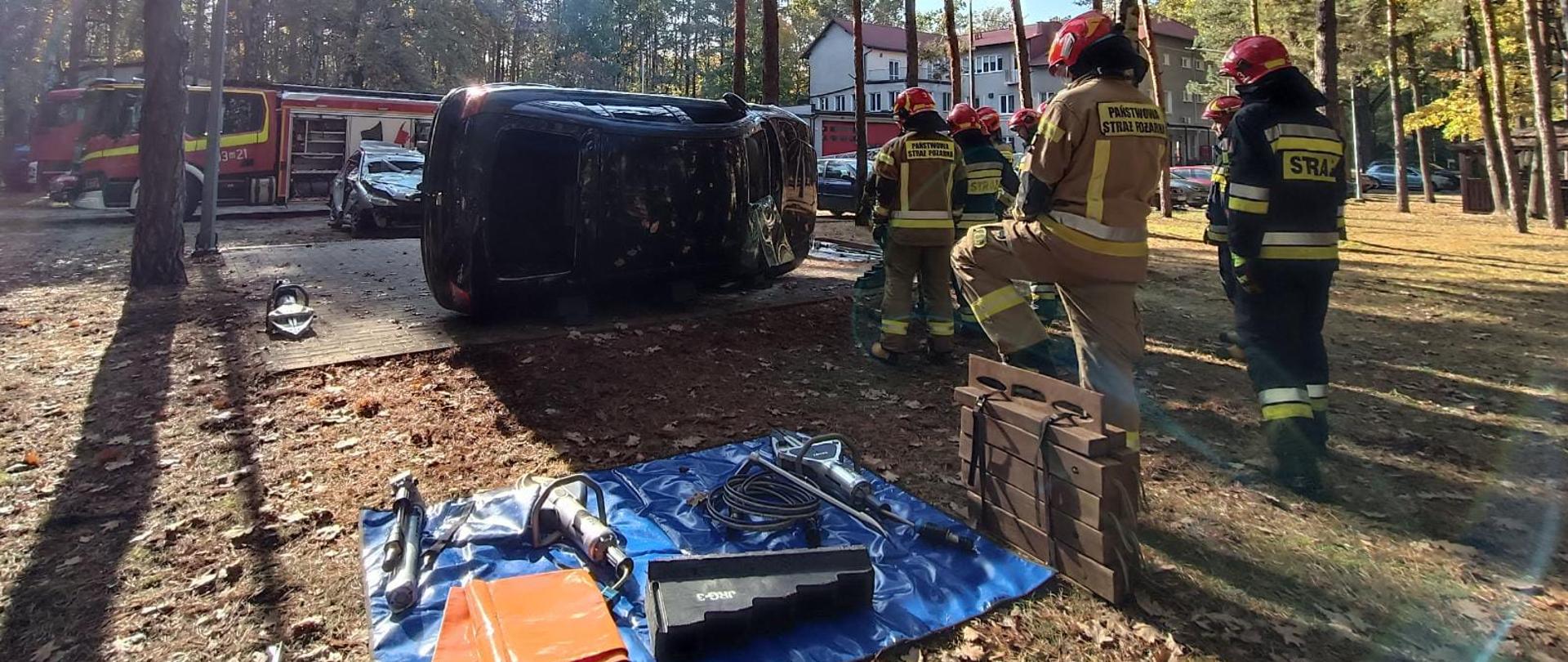Strażacy podczas ćwiczeń z samochodem na boku