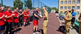 Komendant Powiatowy PSP w Żyrardowie st. bryg. Mariusz Tymoszewicz gratuluje strażakowi i wręcza mu dyplom.