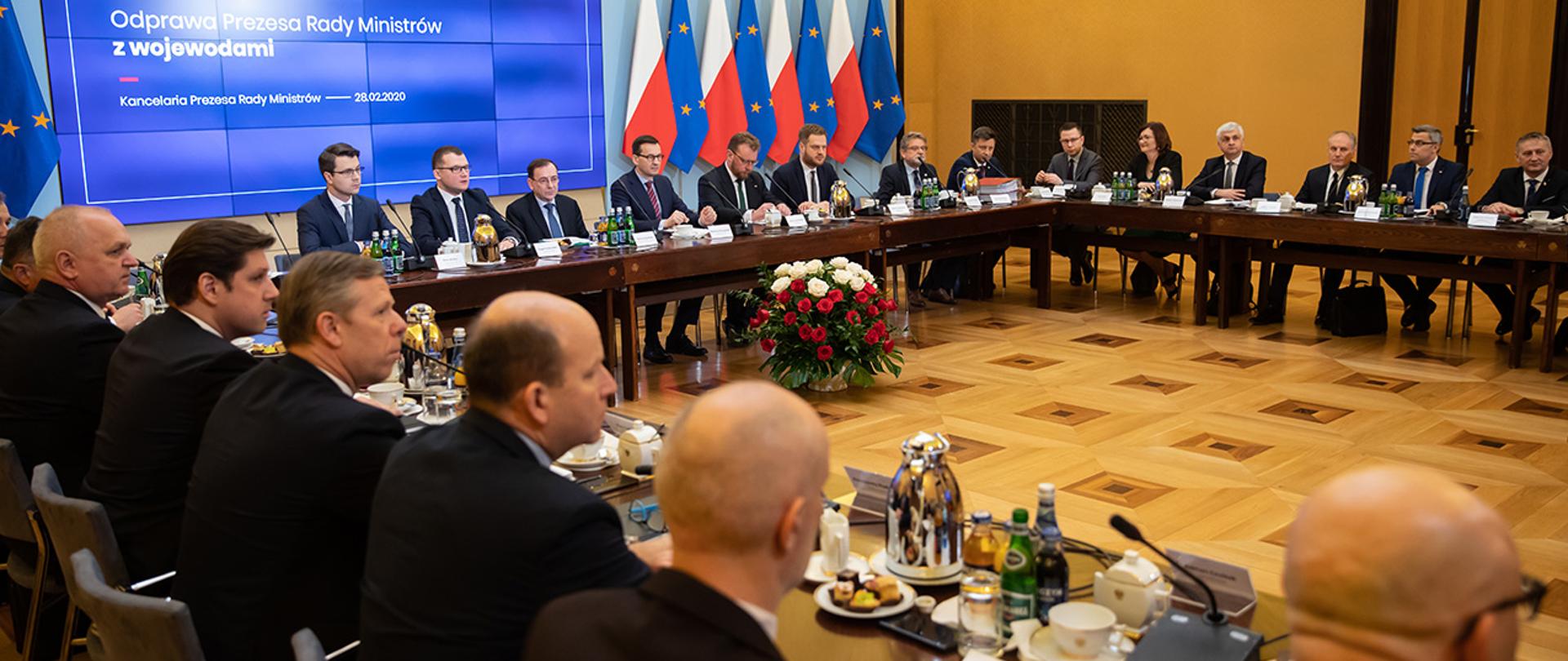 Na zdjęciu widać siedzących przy stole w trakcie litery U m.in.premiera Mateusza Morawieckiego, ministra Mariusza Kamińskiego, ministra zdrowia Łukasza Szumowskiego, wiceministra Pawła Szefernakera i wojewodów.