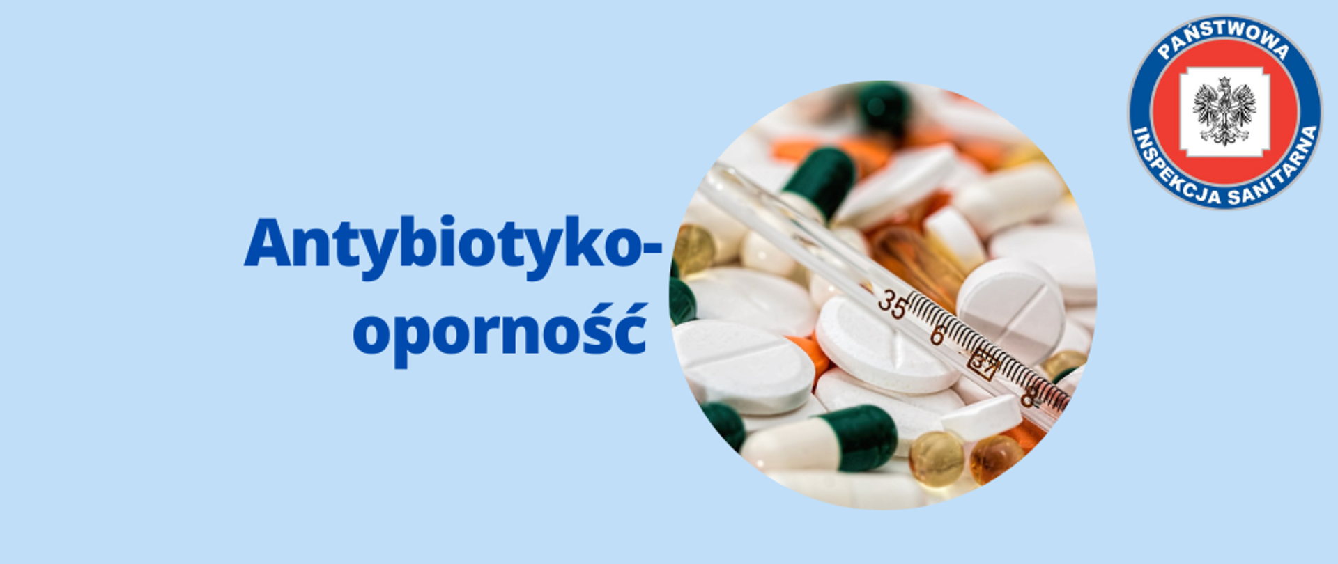 Baner przedstawiający tytuł artykułu z hasłem "Antybiotykooporność". Po prawej stronie znajduje się okrągłe zdjęcie kolorowych lekarstw wyglądających na antybiotyki z termometrem na wierzchu. W prawym górnym rogu umieszczono logo Państwowej Inspekcji Sanitarnej. Całość na niebieskim tle pasującym do kolorystyki strony internetowej.