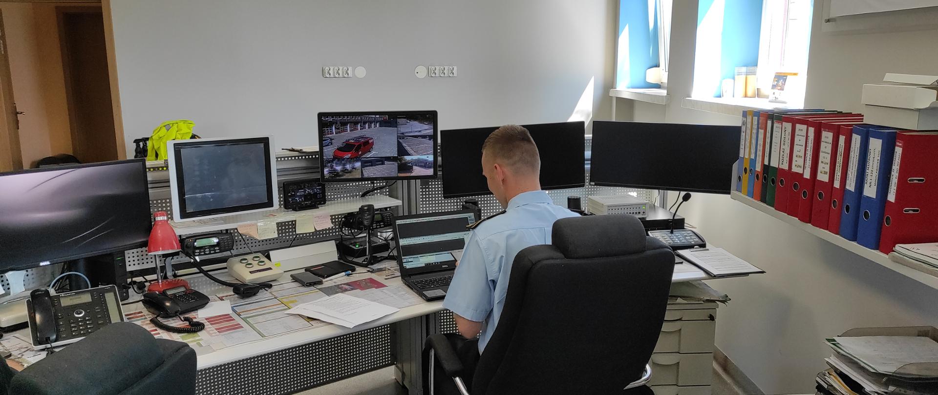 Dyżurny Operacyjny Powiatu Państwowej Straży Pożarnej przed zapasowym stanowiskiem kierowania. 