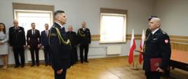 Zdjęcie przedstawia Zastępcę Podlaskiego Komendanta Wojewódzkiego Państwowej Straży Pożarnej brygadiera Marcina Bielakowicza podczas przyjmowania meldunku od nowo powołanego Komendanta Powiatowego Państwowej Straży Pożarnej w Zambrowie młodszego brygadiera Andrzeja Kalinowskiego. Komendanci ubrani w mundury wyjściowe ze sznurem galowym. Uroczystość odbywała się w jednym z pomieszczeń Komendy Powiatowej Państwowej Straży Pożarnej w Zambrowie.
