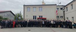 Na placu przed budynkiem jednostki zgromadziła się liczna grupa strażaków oraz zaproszonych gości, aby wspólnie zapozować do pamiątkowego zdjęcia. To zbiorowe portretowanie stanowi uroczyste podsumowanie obchodów, podkreślając jedność i profesjonalizm formacji w dniu ich święta.