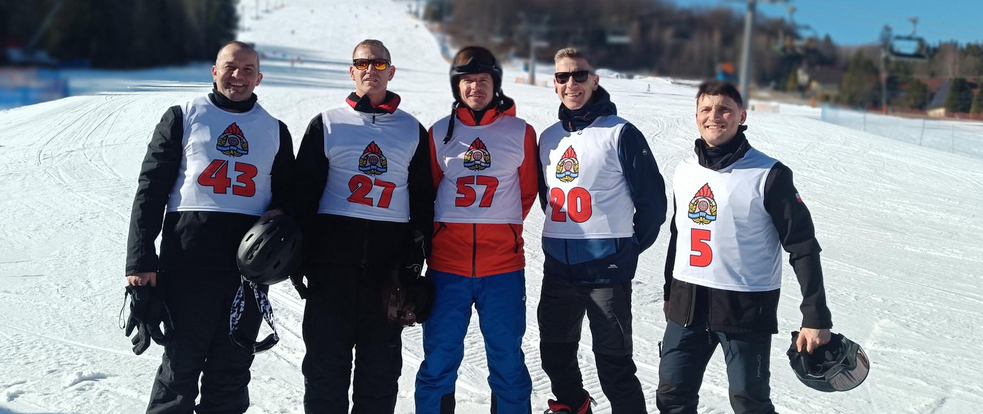 Na zdjęciu pięciu narciarzy pozujących na stoku narciarskim