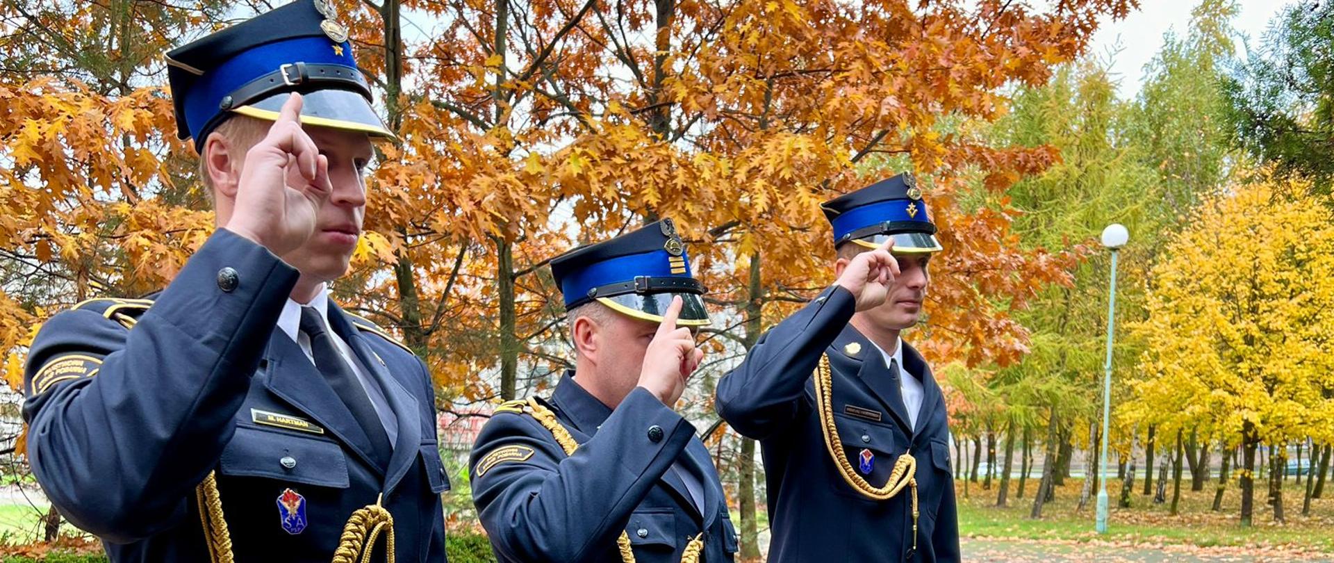 Zdjęcie przedstawia strażaków podczas złożenia znicza pod tablicą pamięci