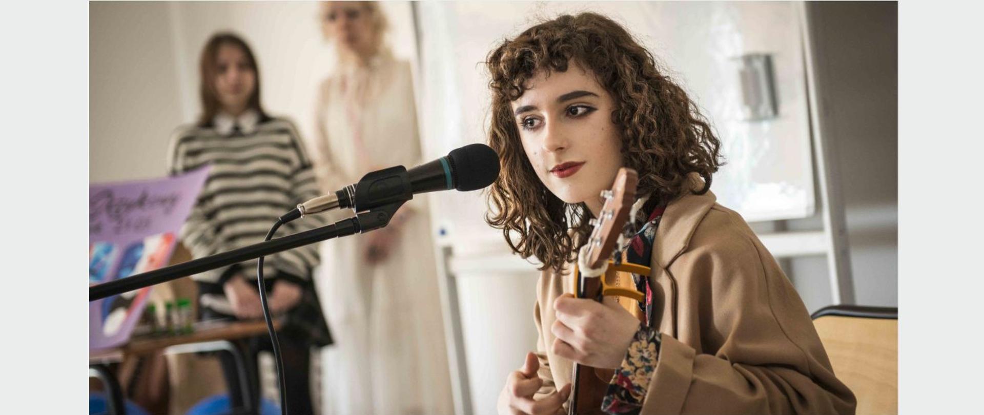 Młoda kobieta śpiewająca i grająca na mandolinie.