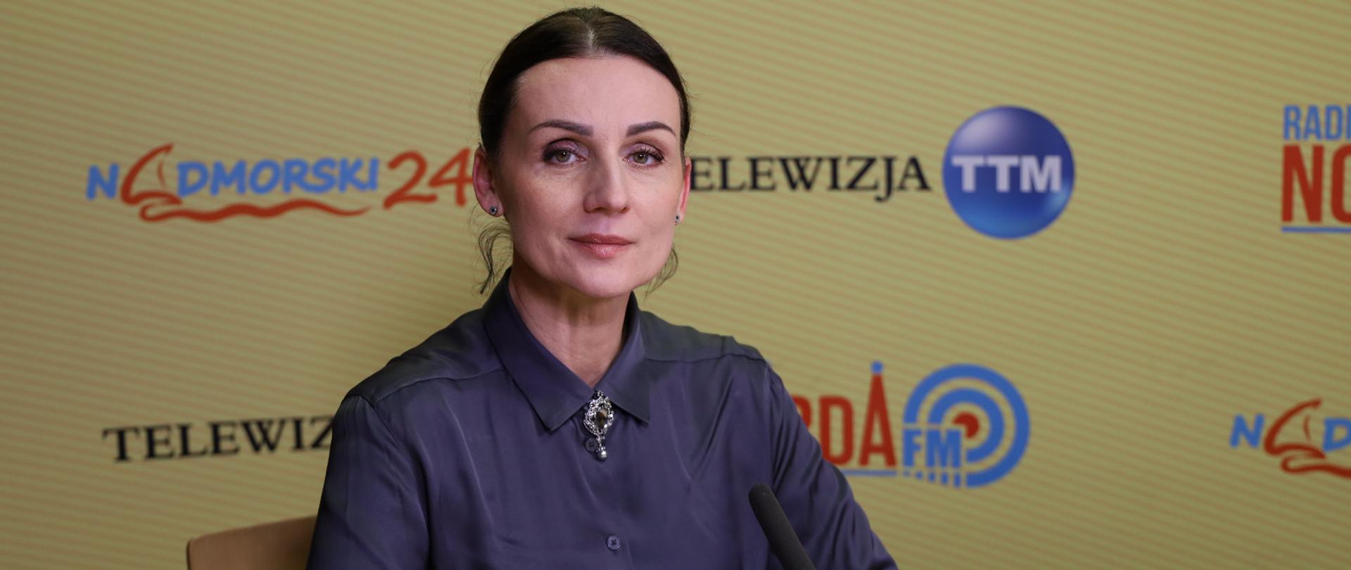 kobieta siedzi w studio telewizyjnym przed mikrofonem