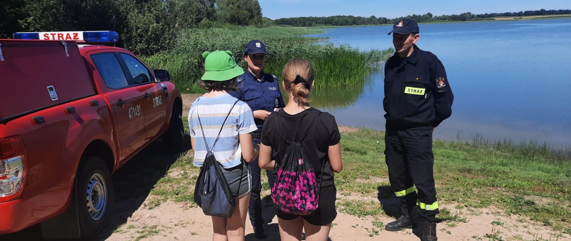 Zdjęcie przedstawia funkcjonariuszkę Policji, strażaka oraz dwie dziewczynki.
