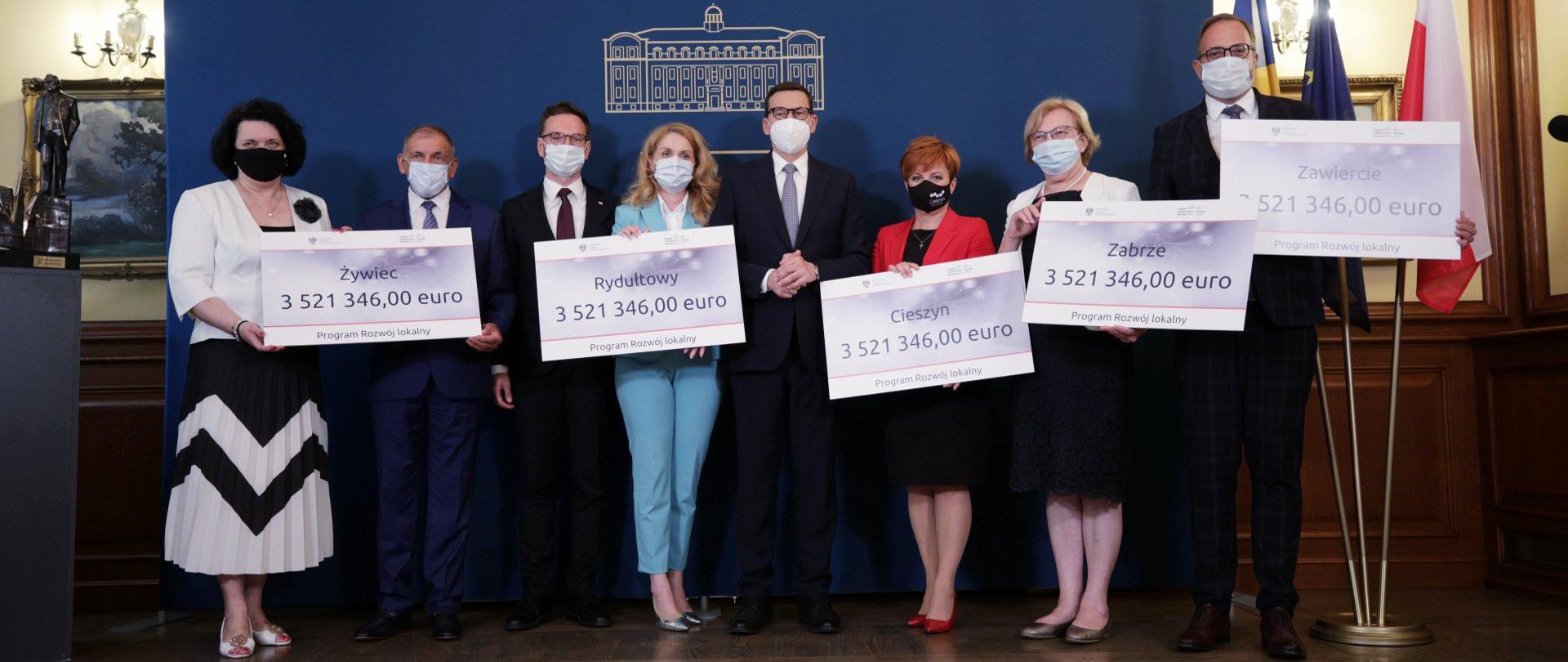 uczestnicy spotkania pokazują symboliczne czeki z kwotami dofinansowania z Funduszy Norweskich i EOG