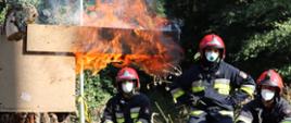 Zdjęcie przedstawia strażaków PSP z terenu województwa pomorskiego, siedzących i obserwujących rozwój pożaru w modułowym wielokontenerowym symulatorze do nauki i doskonalenia gaszenia pożarów wewnętrznych.