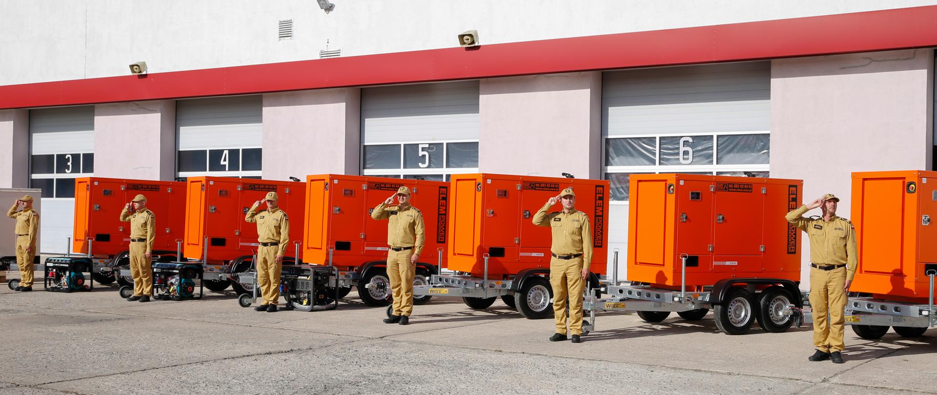 Strażacy salutują. W tle agregaty prądotwórcze.