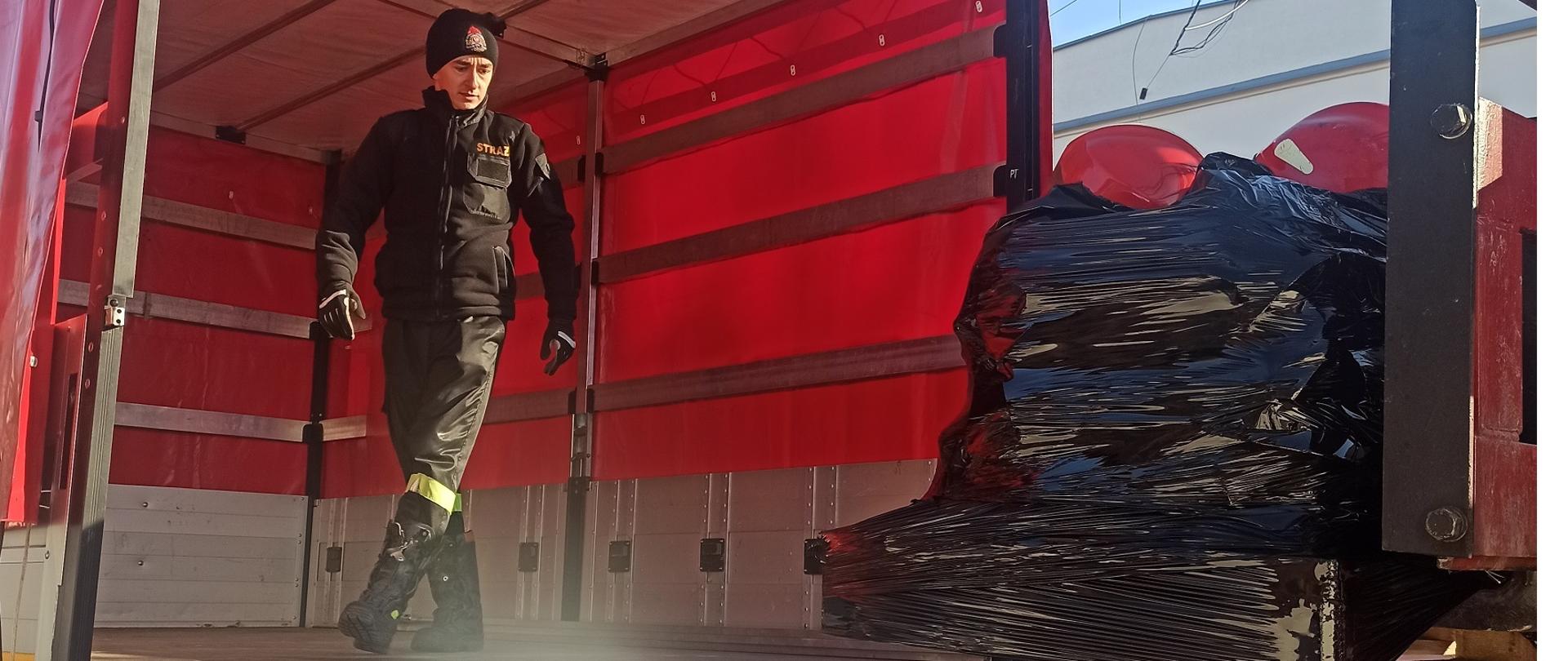 Na zdjęciu kierowca układający sprzęt na samochodzie.