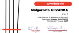 Dyplom wyróżnienie w IV KONKURSIE SKRZYPCOWYM im. Wandy Wiłkomirskiej dla Małgorzaty Grzanki. Ozdobny napis Wiłkomirska w kolorze jasnobrązowym na białym tle, po lewej stronie struny skrzypcowe.
