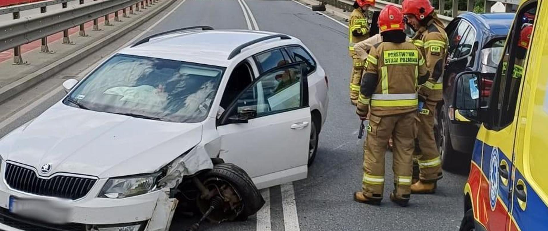 Uszkodzony samochód osobowy a obok strażacy