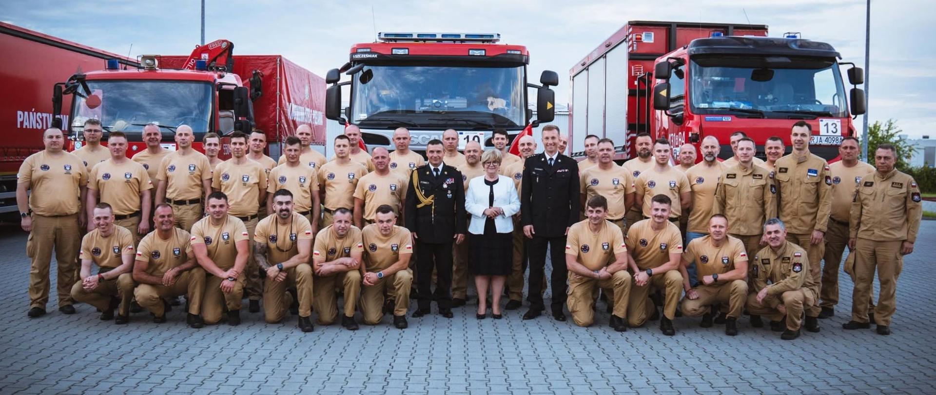 Podkarpaccy strażacy wyruszyli na międzynarodowe ćwiczenia do Mołdawii. Zdjęci grupowe strażaków, stojących na placu JRG. Za strażakami widać samochody pożarnicze.
