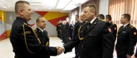 Na zdjęciu st. ogn. Grzegorz Kowalski otrzymujący życzenia od funkcjonariuszy KP PSP w Wałczu. W tle pododdział strażacki ustawiony w dwuszeregu.