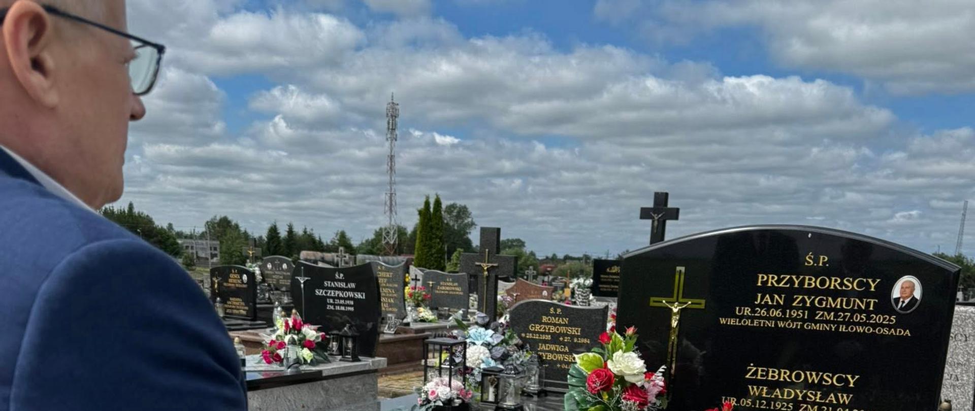 Mężczyzna w garniturze stoi przy grobie 