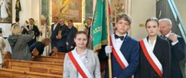 Członkowie pocztu sztandarowego pozują do zdjęcia w kościele. W tle widać obraz przedstawiający św. Izydora Oracza.