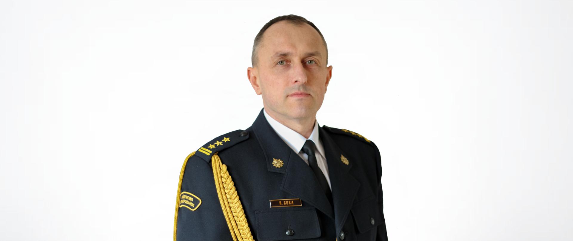 Zdjęcie portretowe z-cy komendanta st. bryg. Rafała Góry na jasnym tle w mundurze galowym.