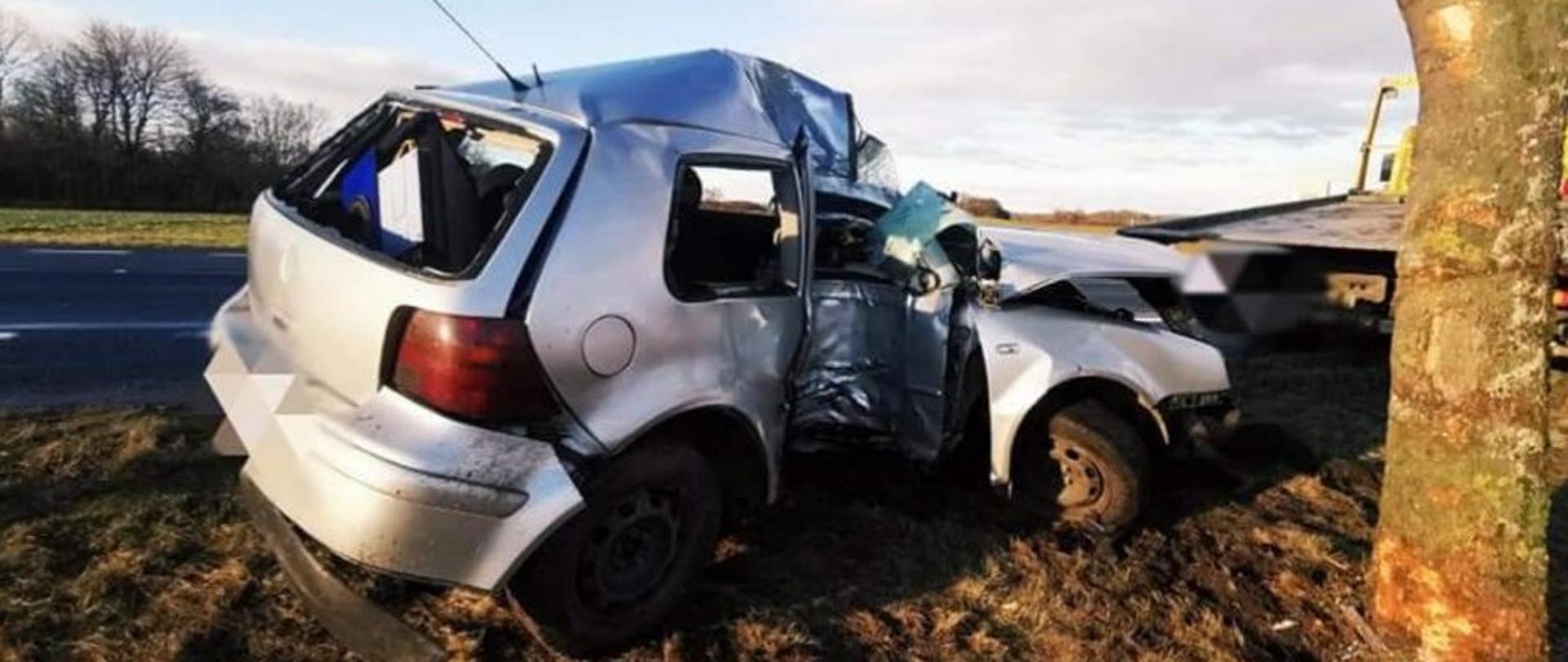 Zdjęcie przedstawia wrak samochodu osobowego oraz drzewo 