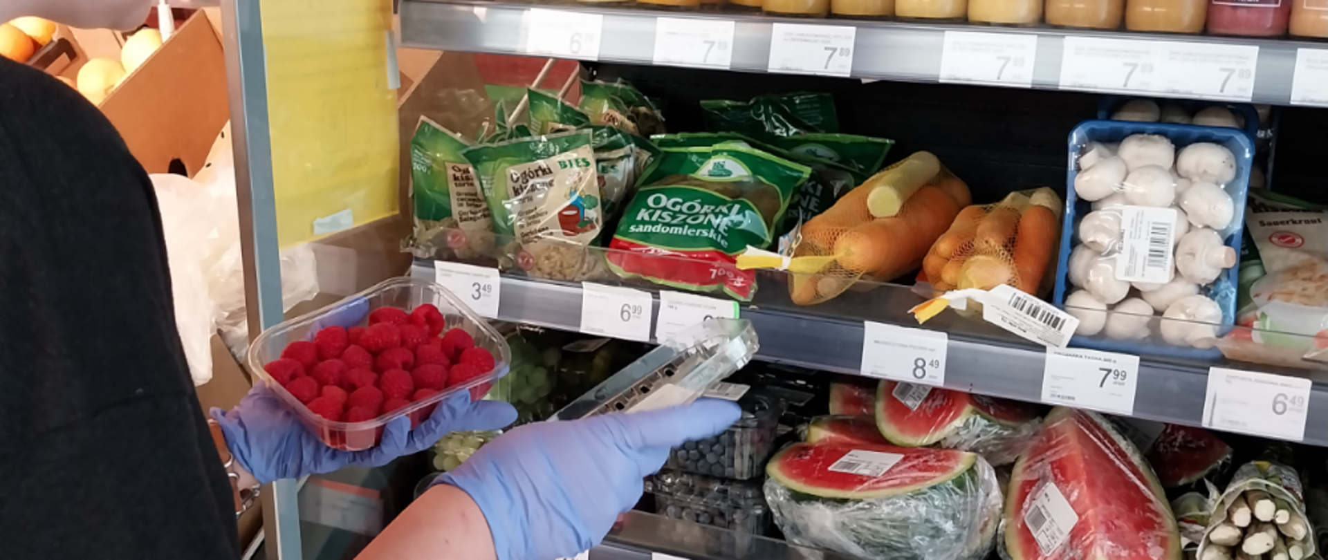 Kobieta rozkładająca warzywa na półkach.