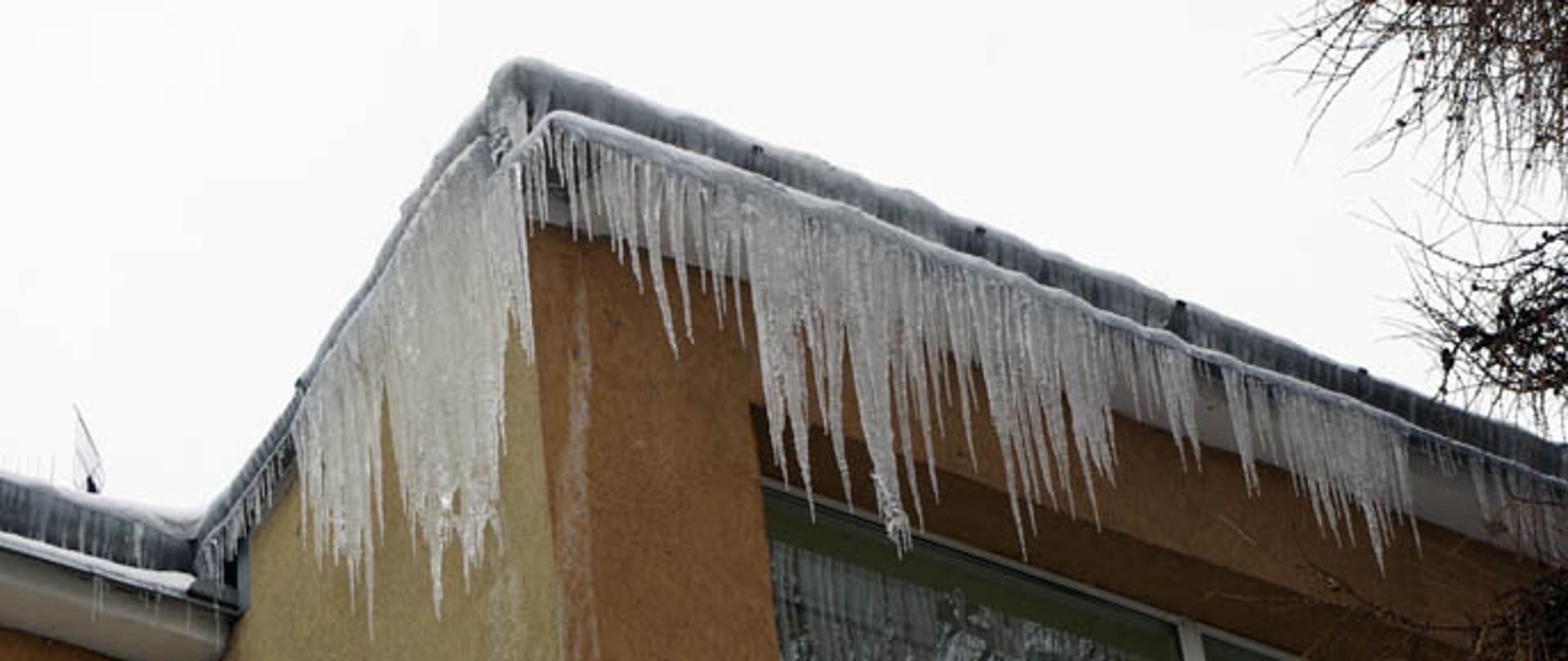Na zdjęciu widzimy zwisające sople lodu z dachu budynku.