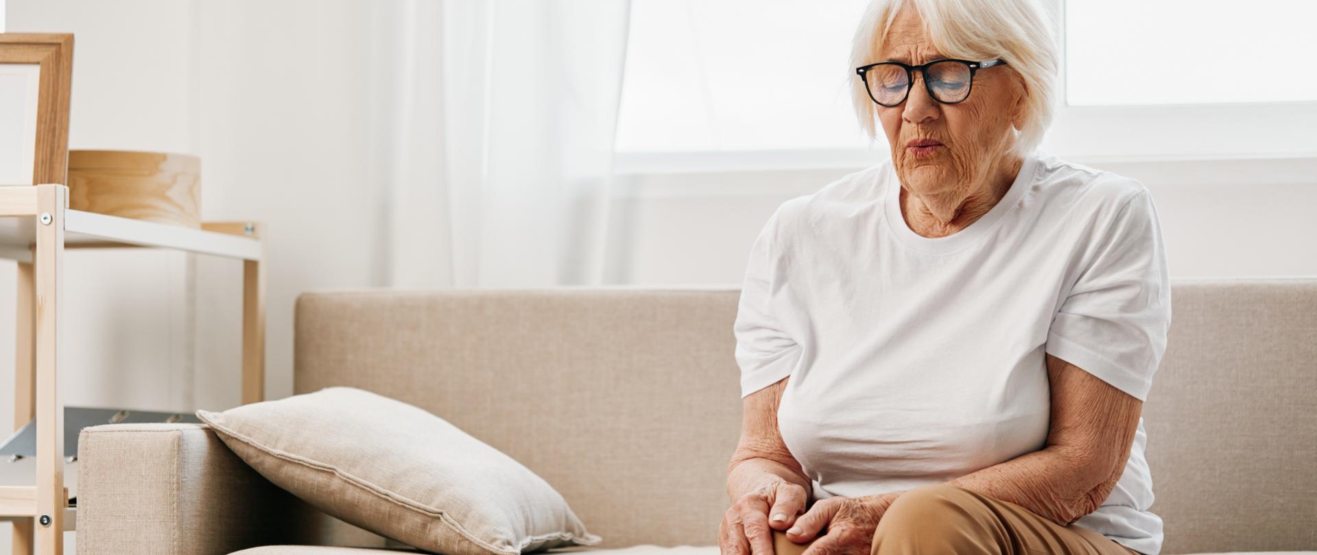 starsza kobieta siedząca na kanapie z bolącym kolanem