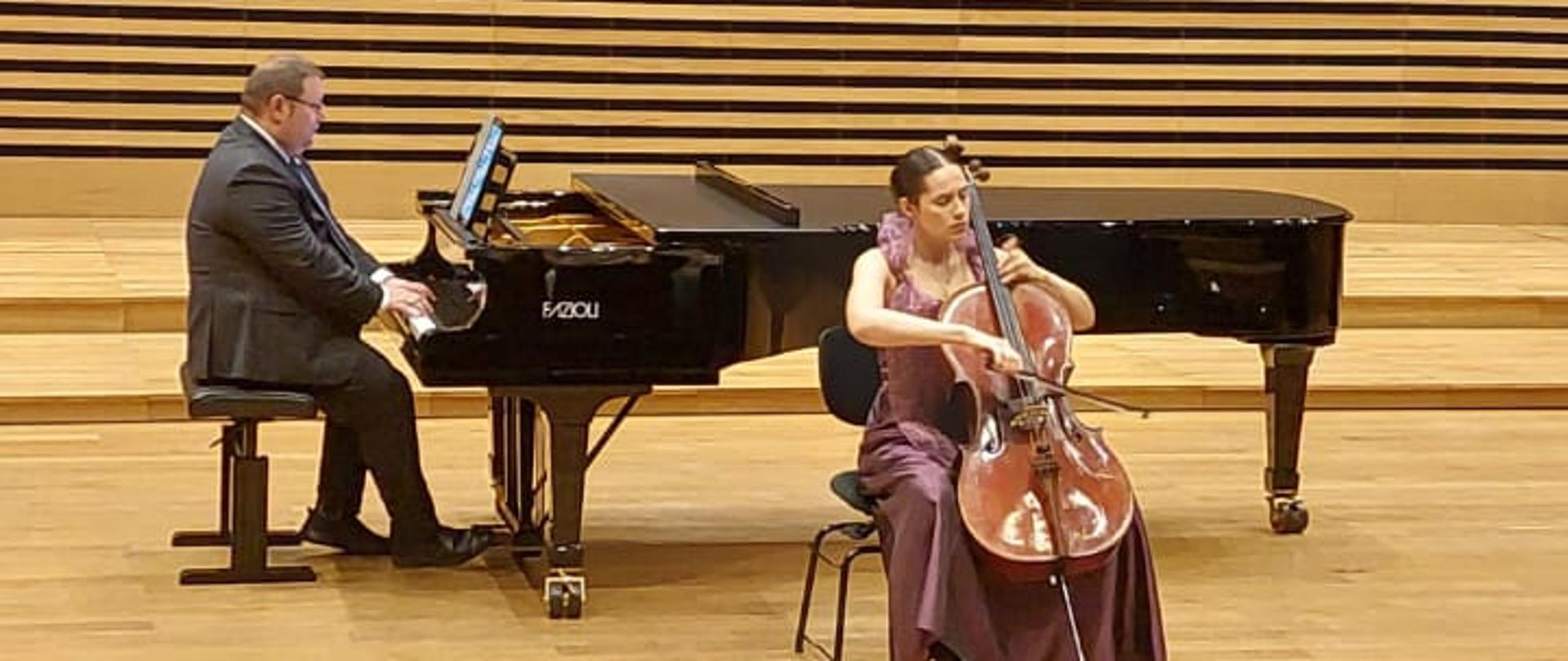 Dziewczyna gra na wiolonczeli, mężczyzna akompaniuje na fortepianie.