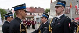 Widok z boku. Zastępca małopolskiego komendanta wojewódzkiego PSP w trakcie wręczania strażakom PSP aktów mianowania na wyższe stopnie służbowe.