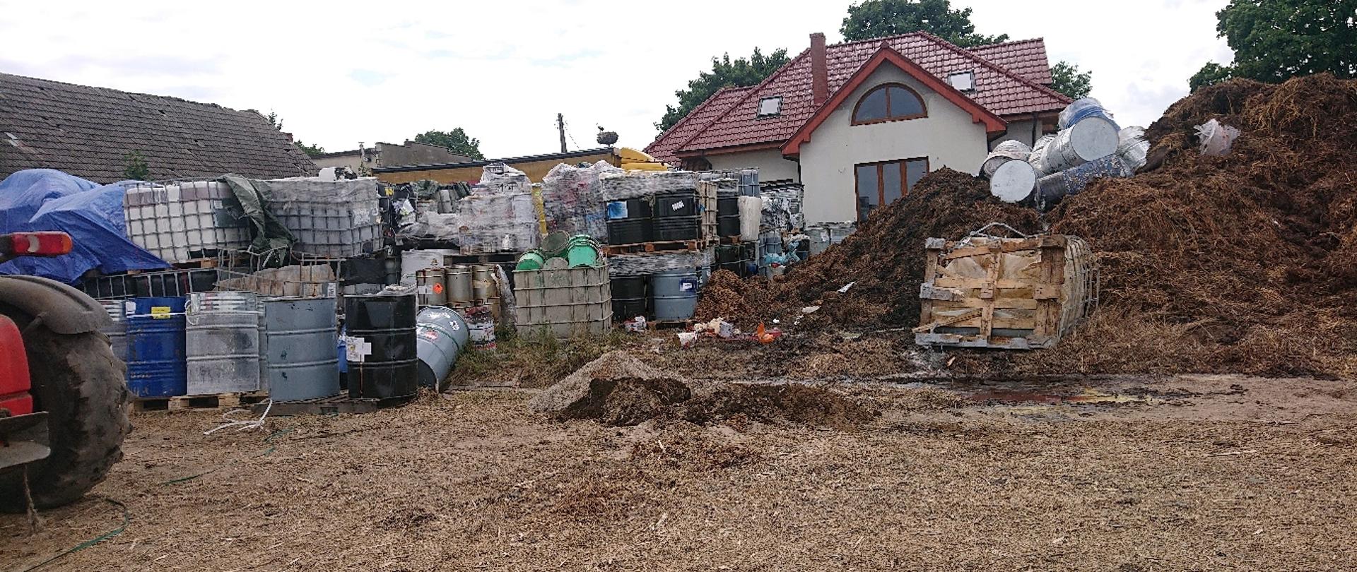 Widać kilkanaście beczek i zbiorników typu mauzer na posesji