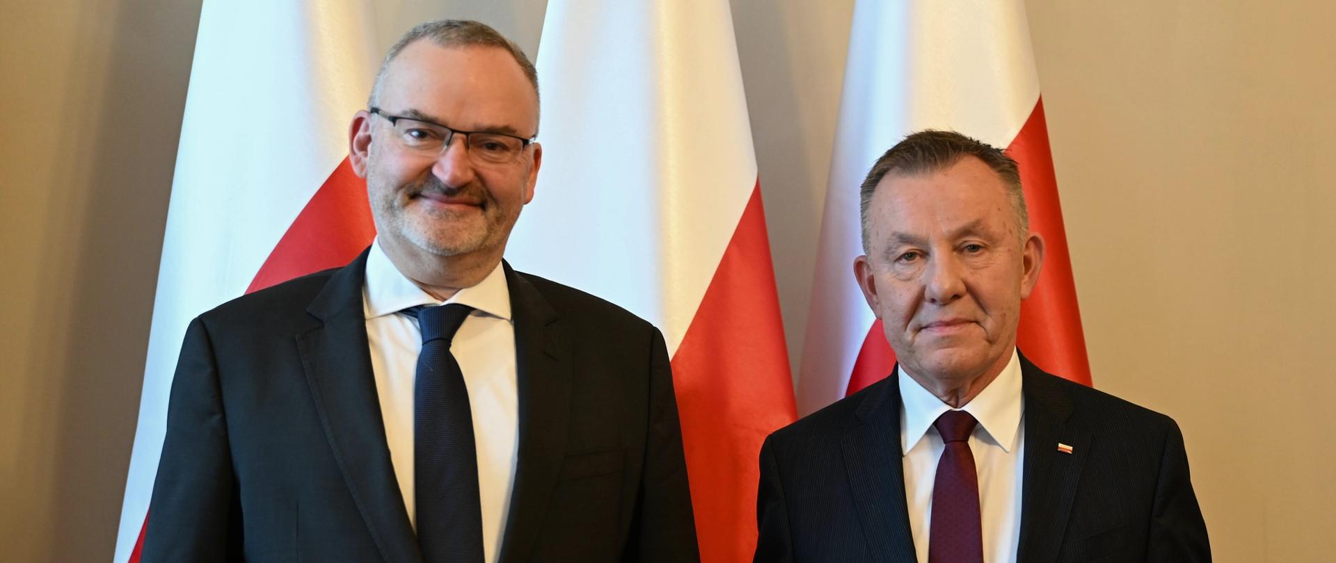 Ambasador Szwajcarii Fabrice Filliez i wojewoda łódzki Karol Młynarczyk na tle biało czerwonych flag