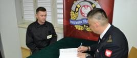Komendant Powiatowy PSP wraz ze strażakiem PSP podpisują akt ślubowania