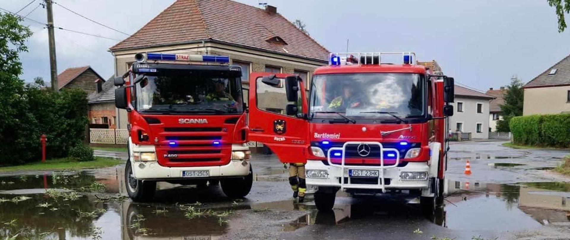 Na zdjęciu widać dwa samochody strażackie oraz budynki mieszkalne