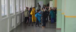 Ćwiczenia ewakuacyjne. Zdjęcie przedstawia korytarz Szkoły Podstawowej nr 4 w Rawiczu. Znajduja sie na nim uczniowie, którzy po ogłoszeniu alarmu ewakuacyjnego opuścili klasy i udaja sie do miejsca zbiórki.
