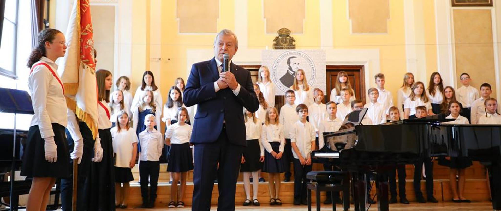 Na środku minister przemawiający, po bokach dzieci ze szkoły