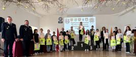 Ogólnopolski Turniej Wiedzy Pożarniczej 2024 - etap powiatowy. Młodzież podczas dekoracji zwycięzców, osoby stoją na podium i w rzędzie z dyplomami i upominkami.