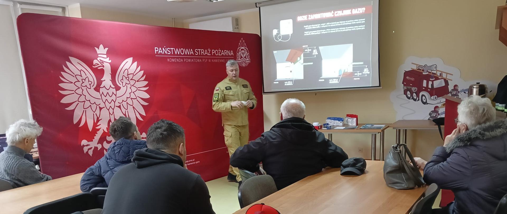 Funkcjonariusz straży pożarnej podczas wręczania czujki tlenku węgla mieszkańcowi powiatu kamiennogórskiego