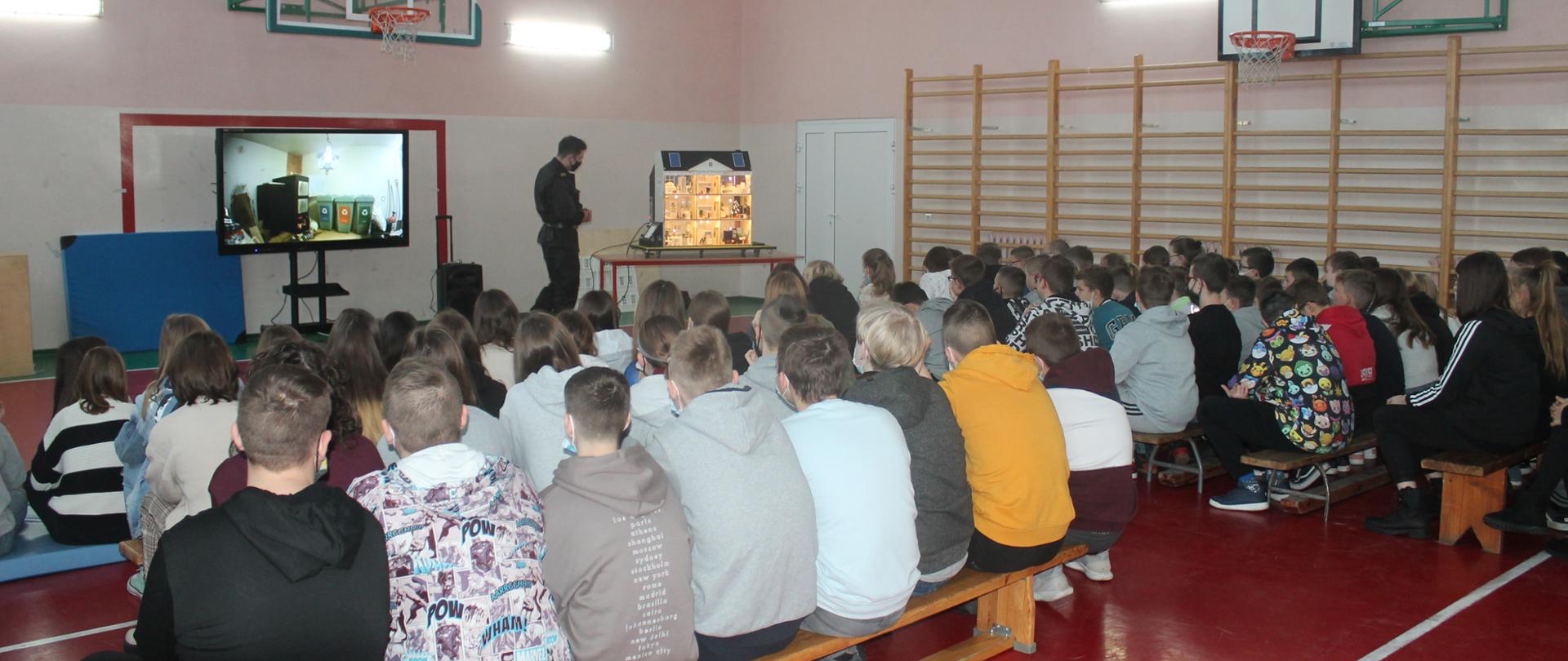 Zdjęcie przedstawia zajęcia prowadzone przez strażaka KP PSP w Kole z wykorzystaniem mobilnego symulatora zagrożeń pożarowych domu jednorodzinnego